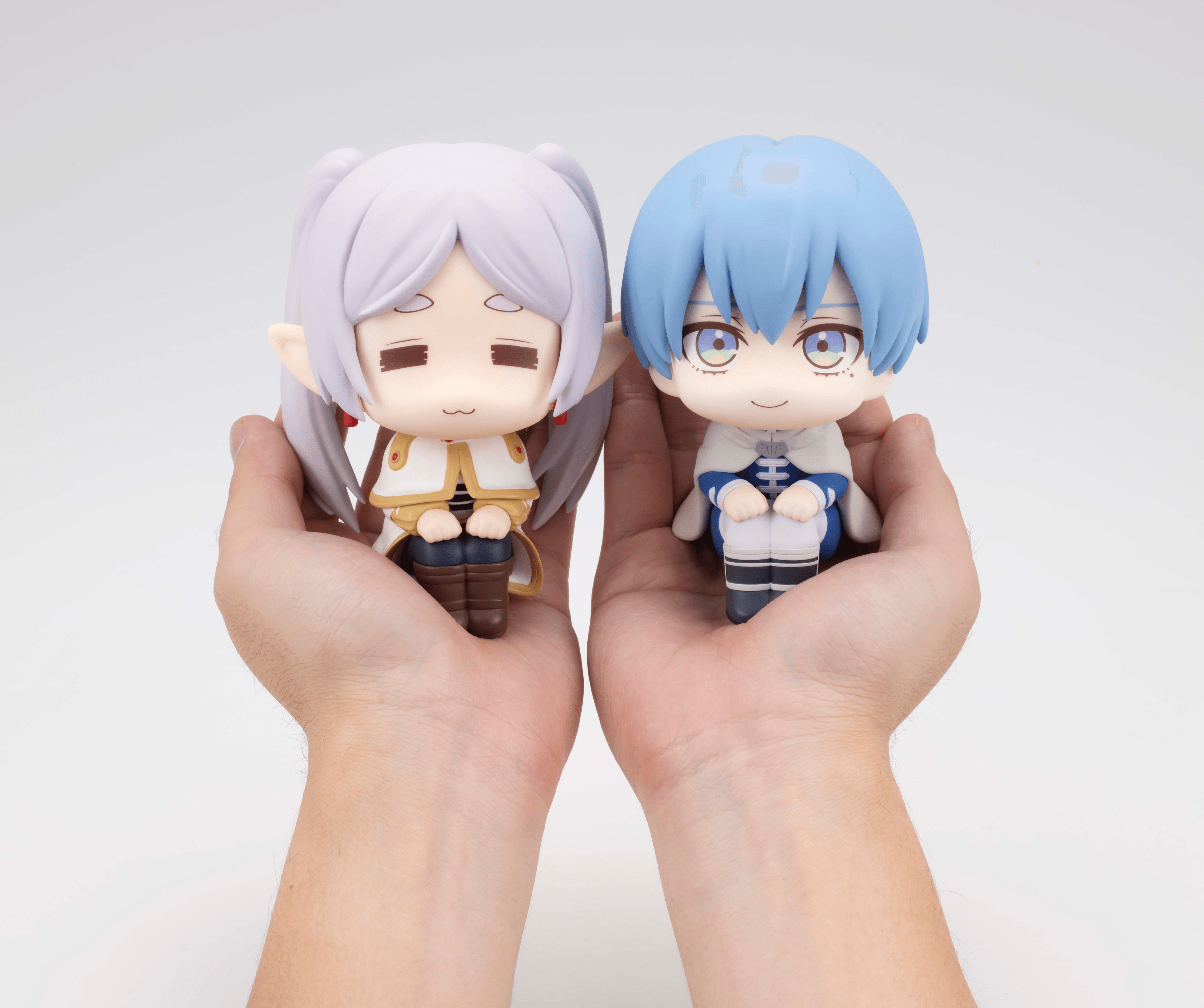 pair of hands holding chibi frieren and chibi himmel