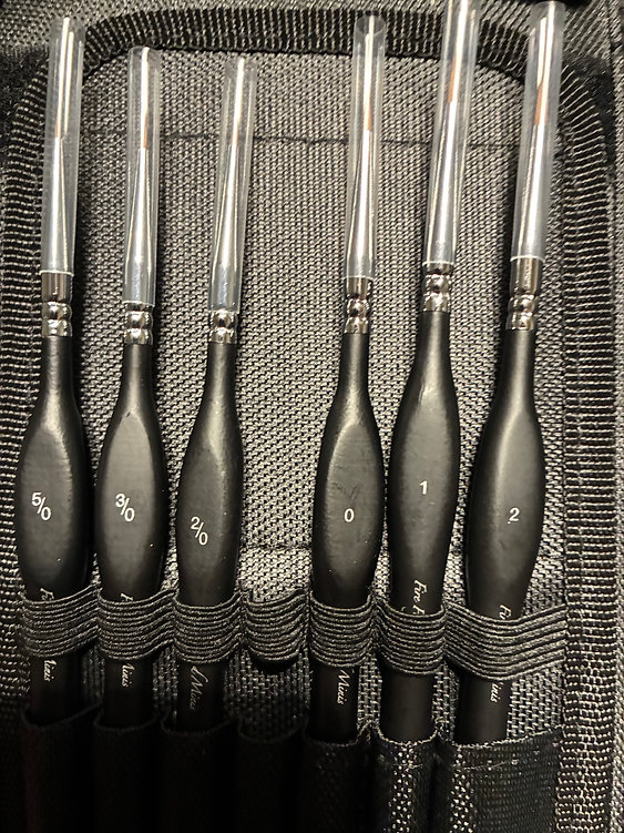 six black handled brushes in holder