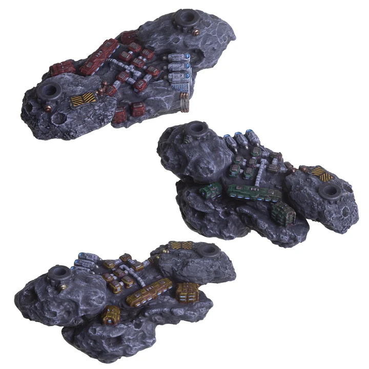 three painted miniature asteroids with small buildings on the surface